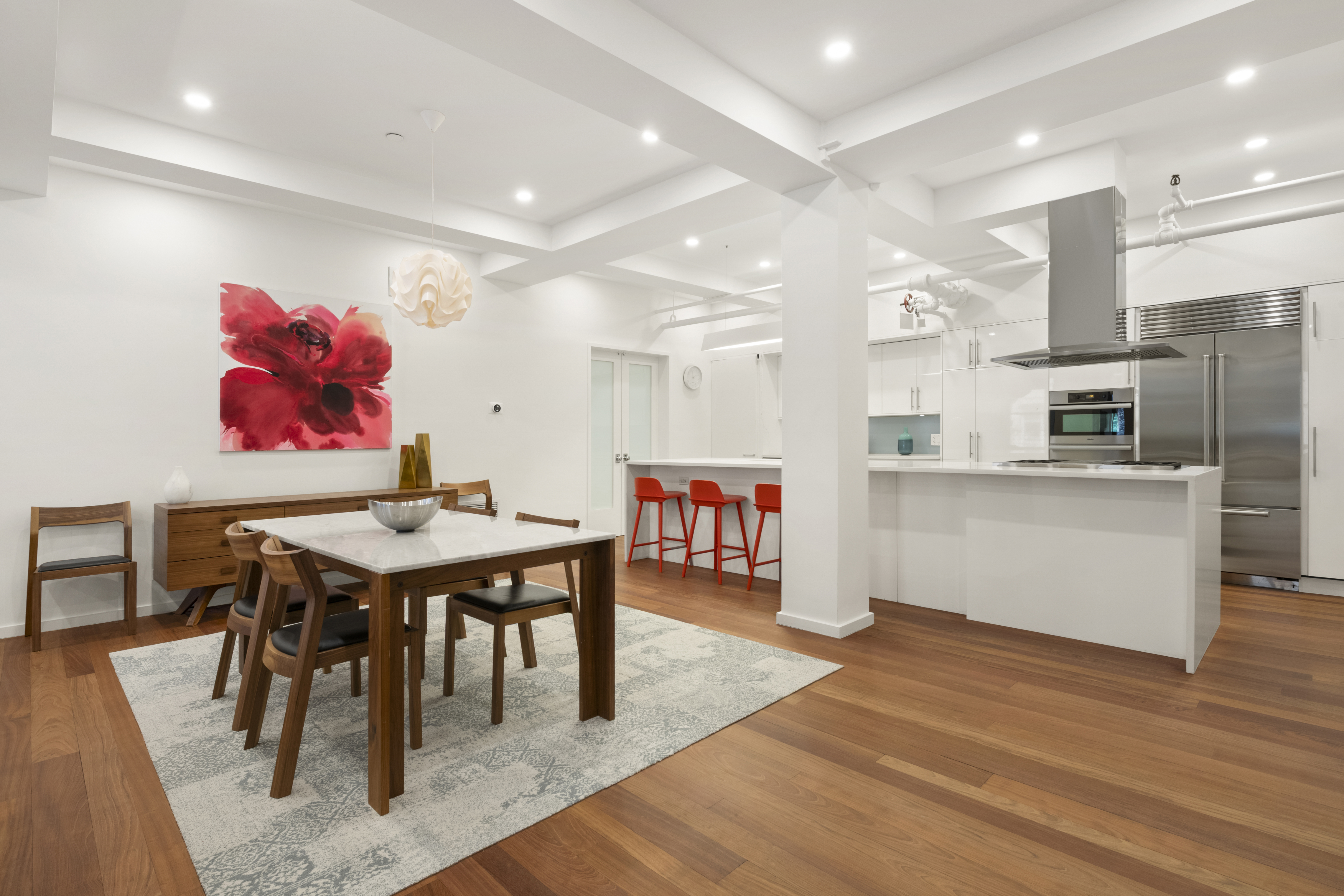 110 Duane Street, Unit 3F Manhattan, NY 10007 - Photo 5 of 14 a open kitchen with stainless steel appliances kitchen island granite countertop a table chairs and a refrigerator