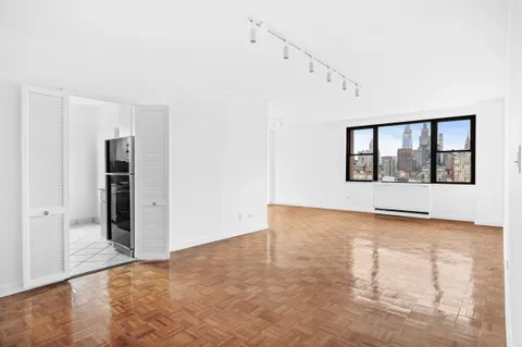 a view of an empty room with window and wooden floor
