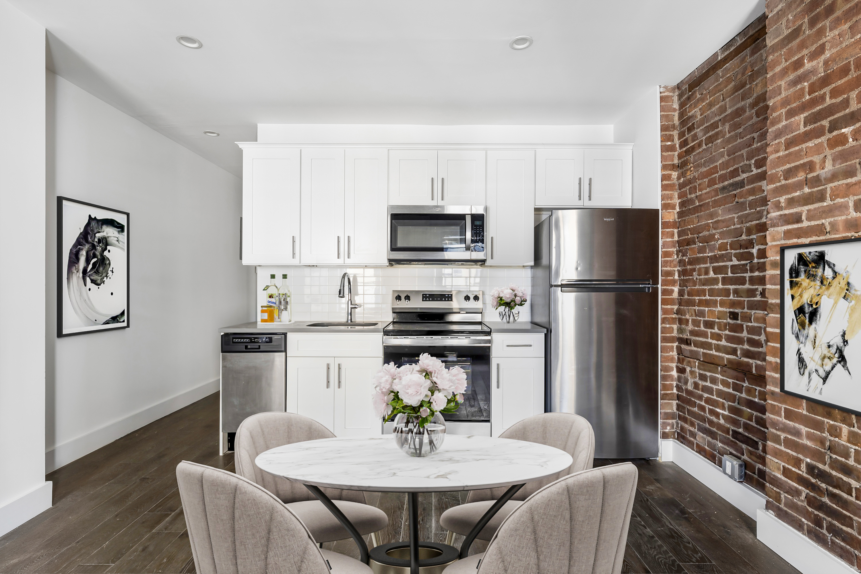 346 West 52nd Street, Unit 5D Manhattan, NY 10019 - Photo 2 of 7 a kitchen with stainless steel appliances a dining table and chairs