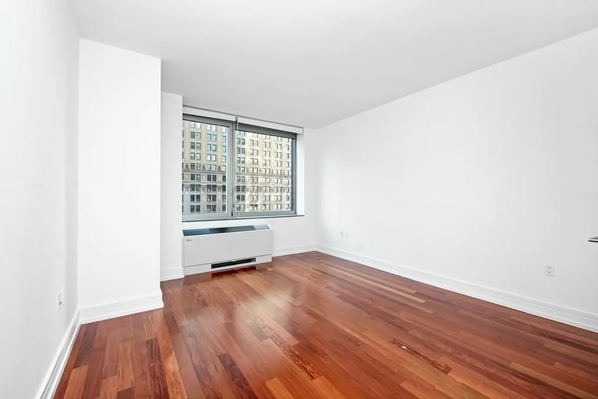 30 West Street, Unit 6B Manhattan, NY 10004 - Photo 11 of 13 an empty room with wooden floor and windows