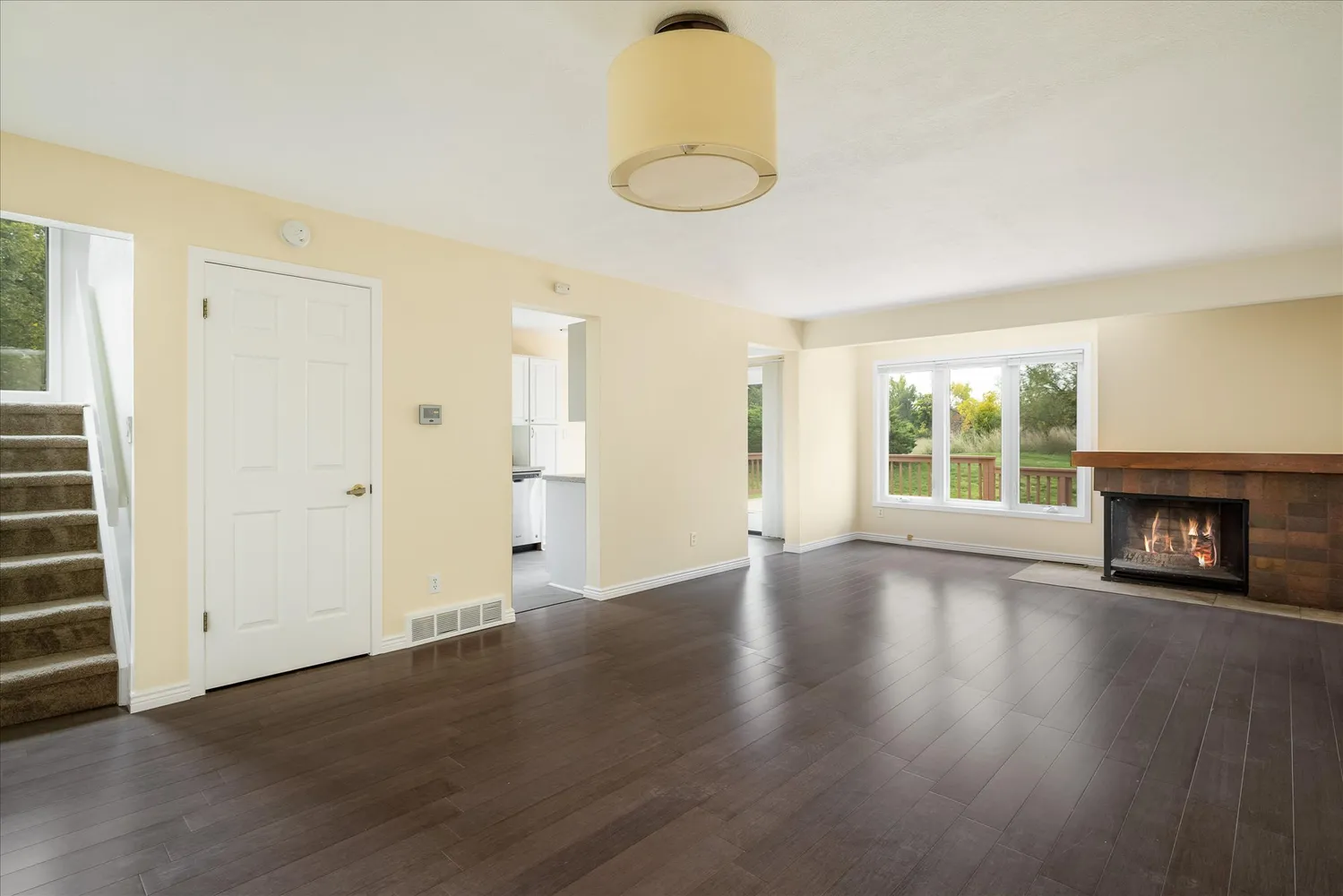 an empty room with wooden floor fireplace and windows