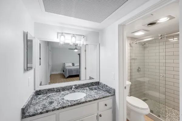 a bathroom with a granite countertop sink toilet and shower