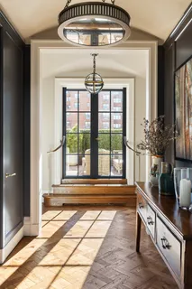 a view of a hallway to a livingroom with wooden floor and a chandelier