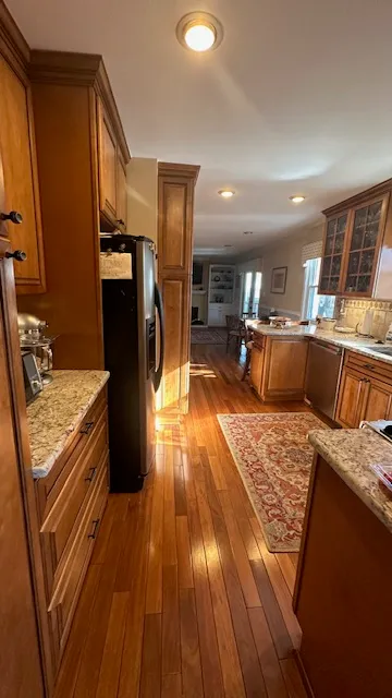 a living room with stainless steel appliances granite countertop furniture wooden floor and a view of kitchen