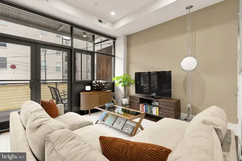 a living room with furniture a flat screen tv and a large window