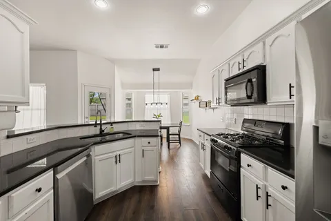 a kitchen with granite countertop stainless steel appliances a stove sink microwave and cabinets