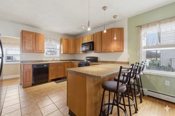 a kitchen with stainless steel appliances granite countertop a stove top oven a sink a dining table and chairs with wooden floor