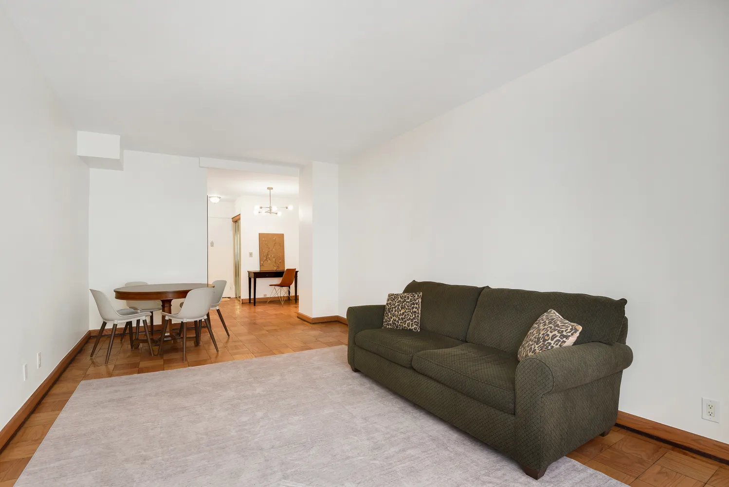 a living room with furniture a dining table and a refrigerator with wooden floor