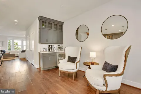 a room with lots of white furniture and wooden floor