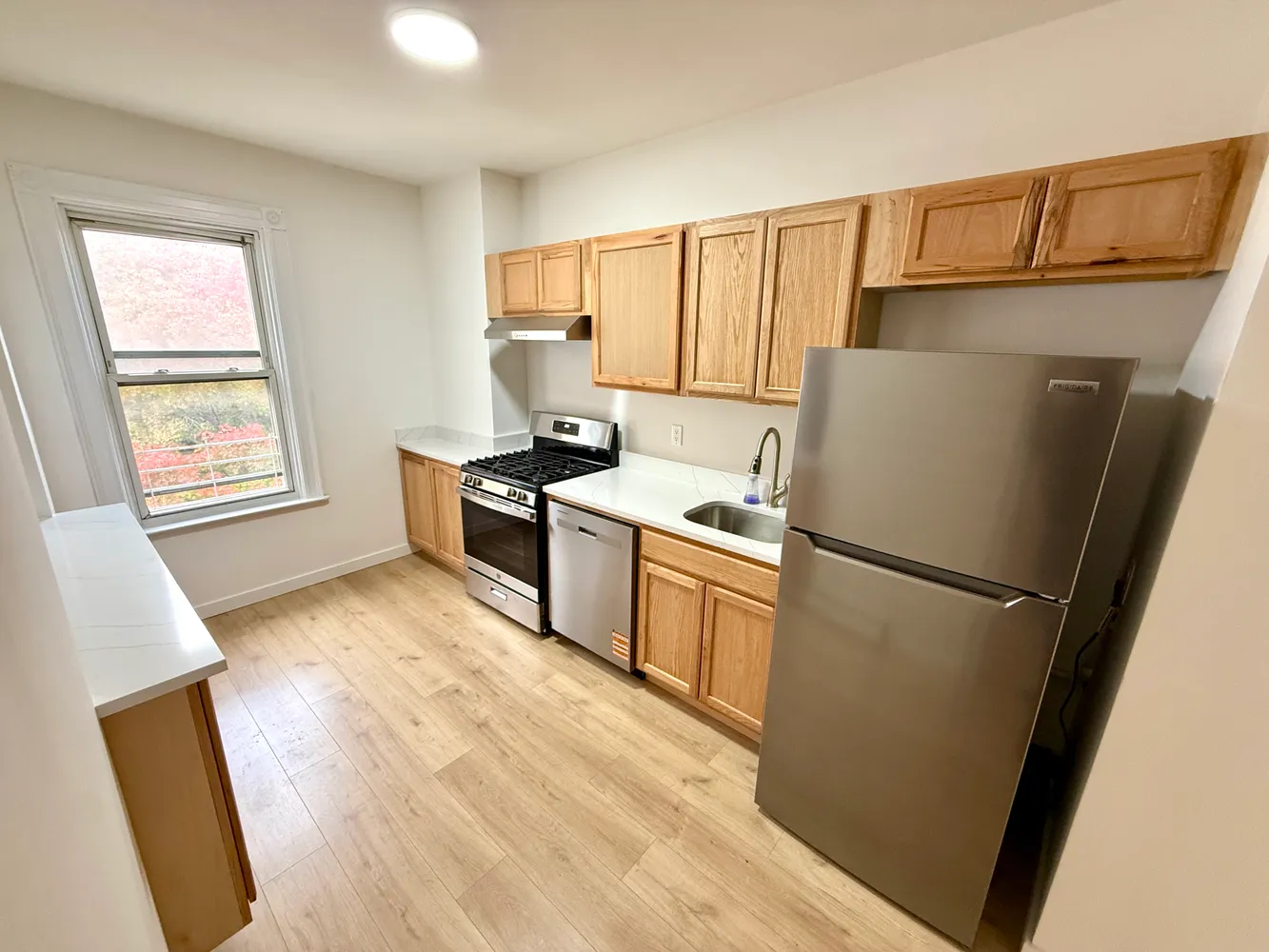 a kitchen with a refrigerator a stove top oven a sink and dishwasher with wooden floor