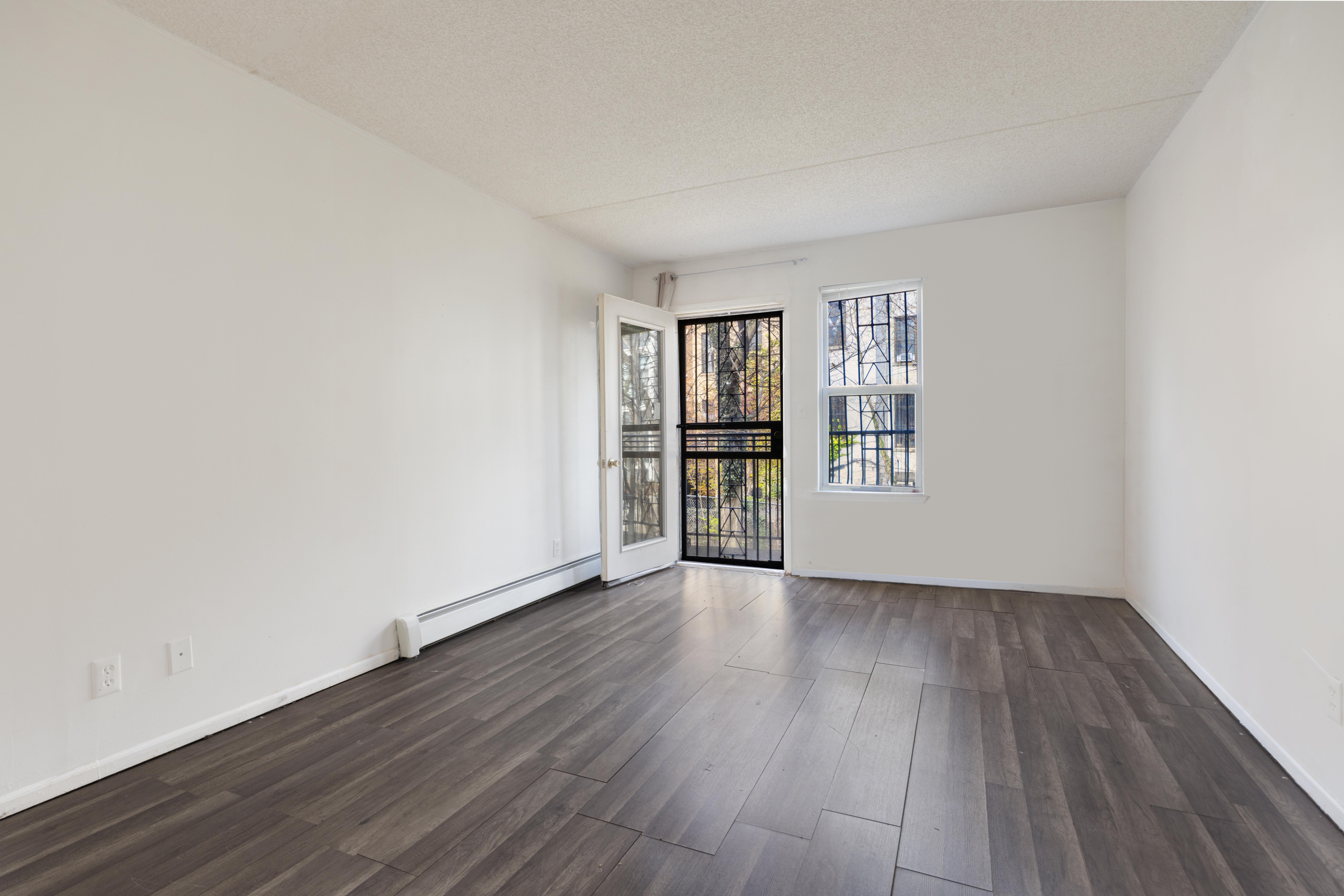 125 West 117th Street Manhattan, NY 10026 - Photo 6 of 23 an empty room with wooden floor and windows