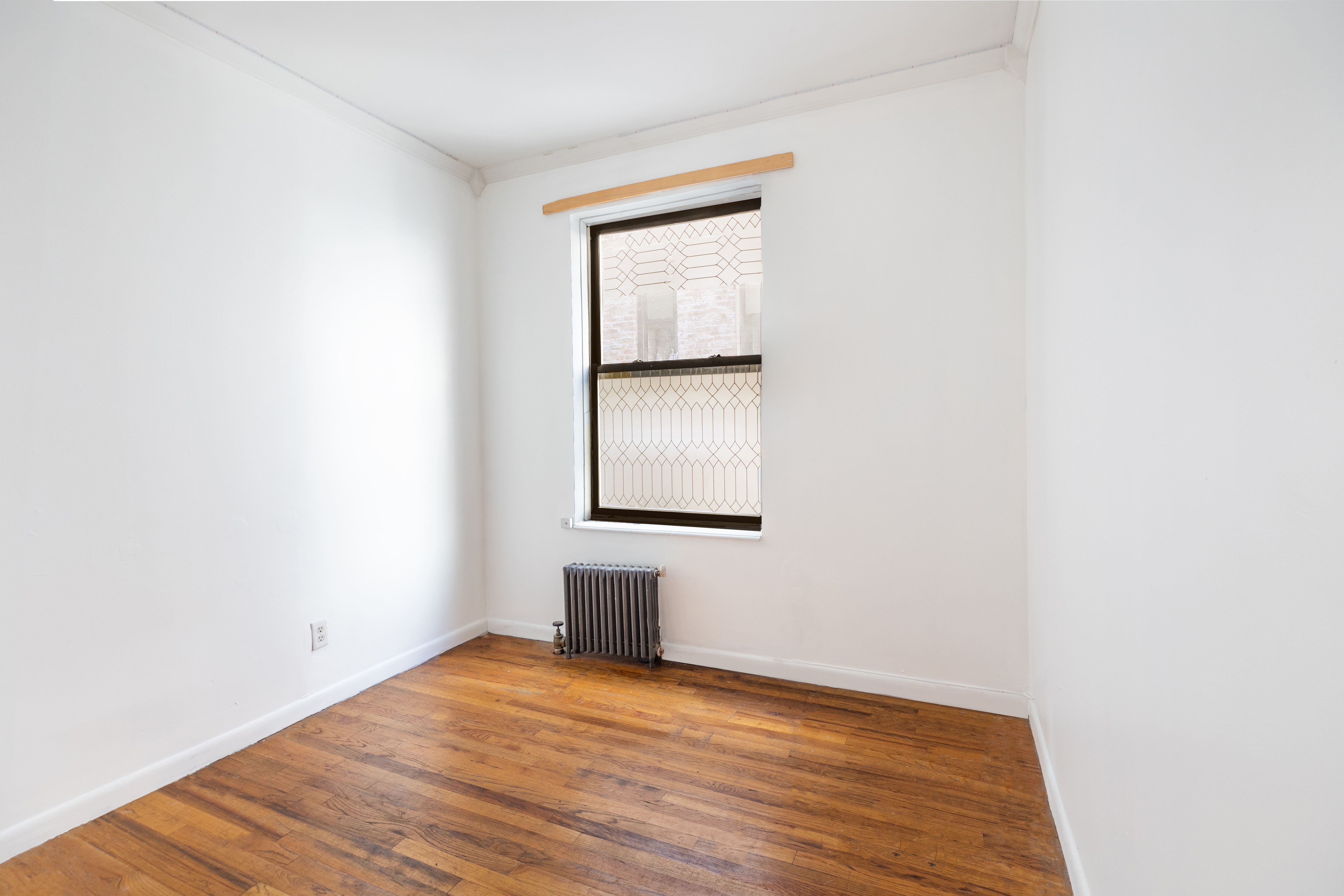 65 West 107th Street, Unit 2D Manhattan, NY 10025 - Photo 4 of 7 a view of an empty room with wooden floor and a window