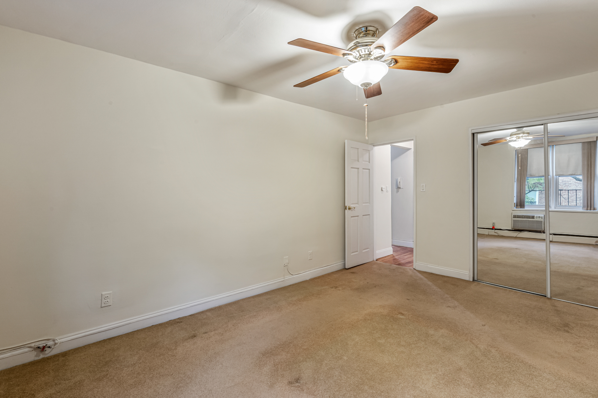 54-44 Little Neck Parkway, Unit 5G Queens, NY 11362 - Photo 12 of 20 an empty room with chandelier fan and kitchen view