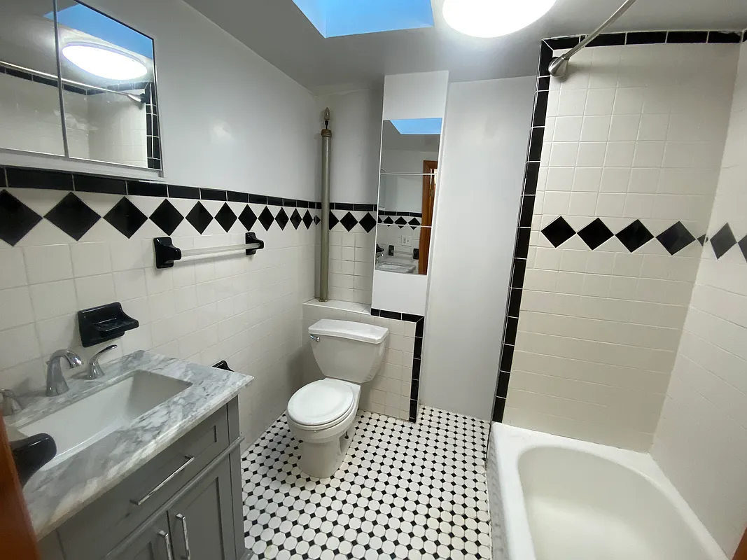 62 Bainbridge Street, Unit 4 Brooklyn, NY 11233 - Photo 7 of 8 a bathroom with a sink a toilet a shower curtain and a mirror