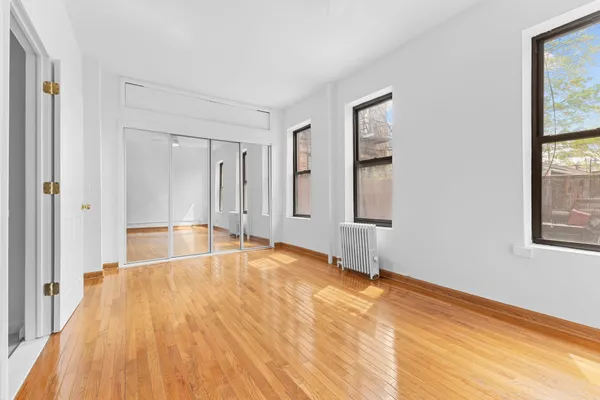 a view of an empty room with window and wooden floor