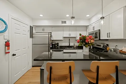 a kitchen with granite countertop a refrigerator stove microwave and cabinets