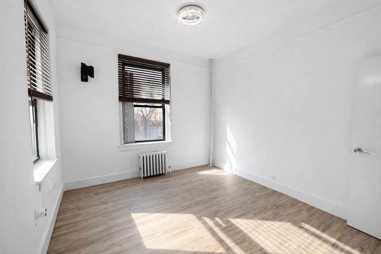 164 West 128th Street, Unit 3C Manhattan, NY 10027 - Photo 6 of 8 a view of an empty room with wooden floor and a window