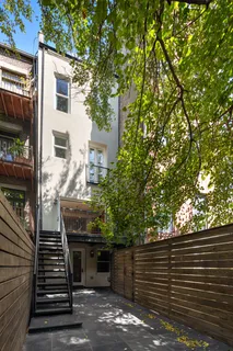 a view of a patio with two couches and deck with wooden floor and fence and a barbeque