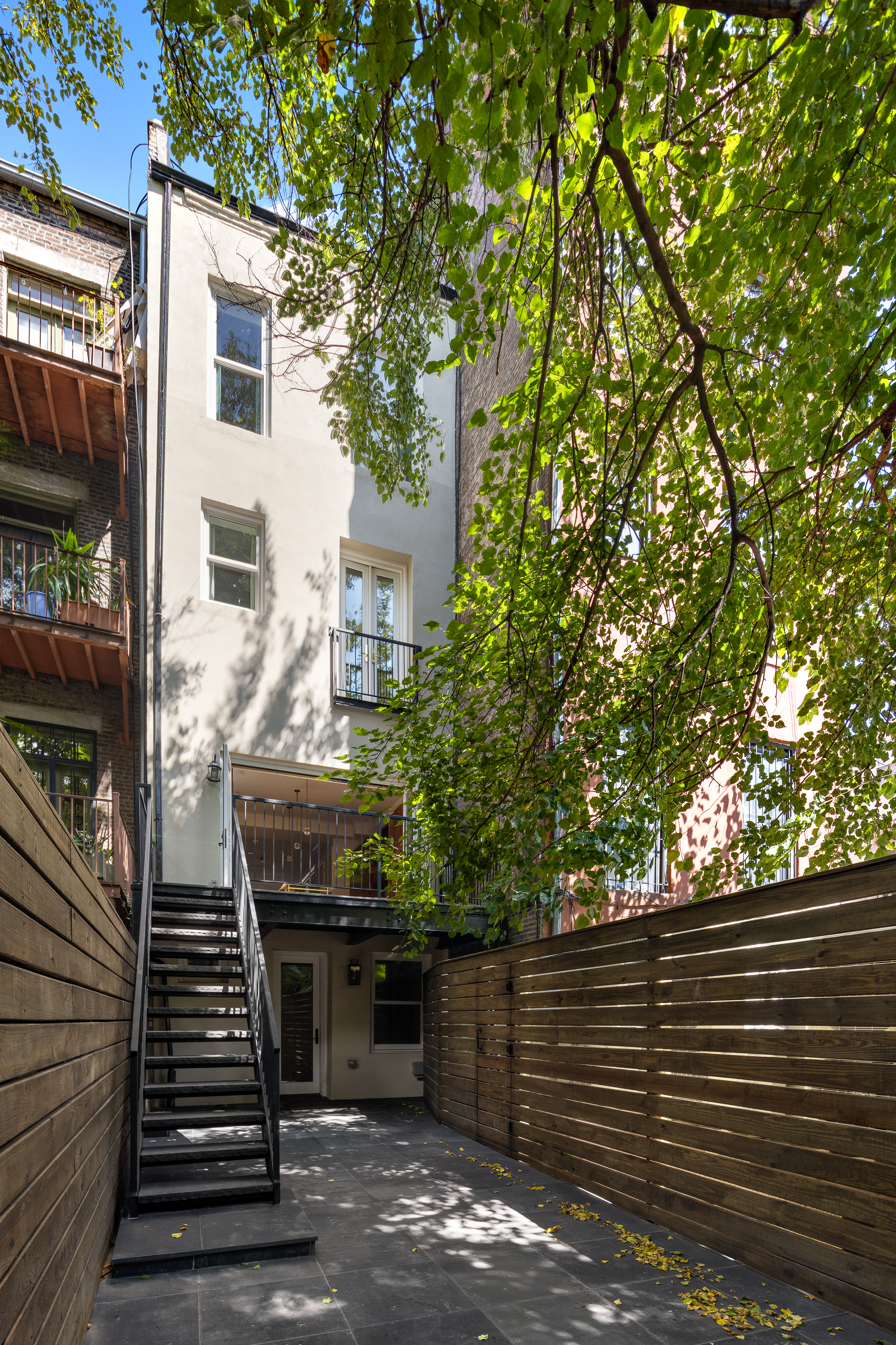 304 West 137th Street Manhattan, NY 10030 - Photo 25 of 26 a view of a patio with two couches and deck with wooden floor and fence and a barbeque