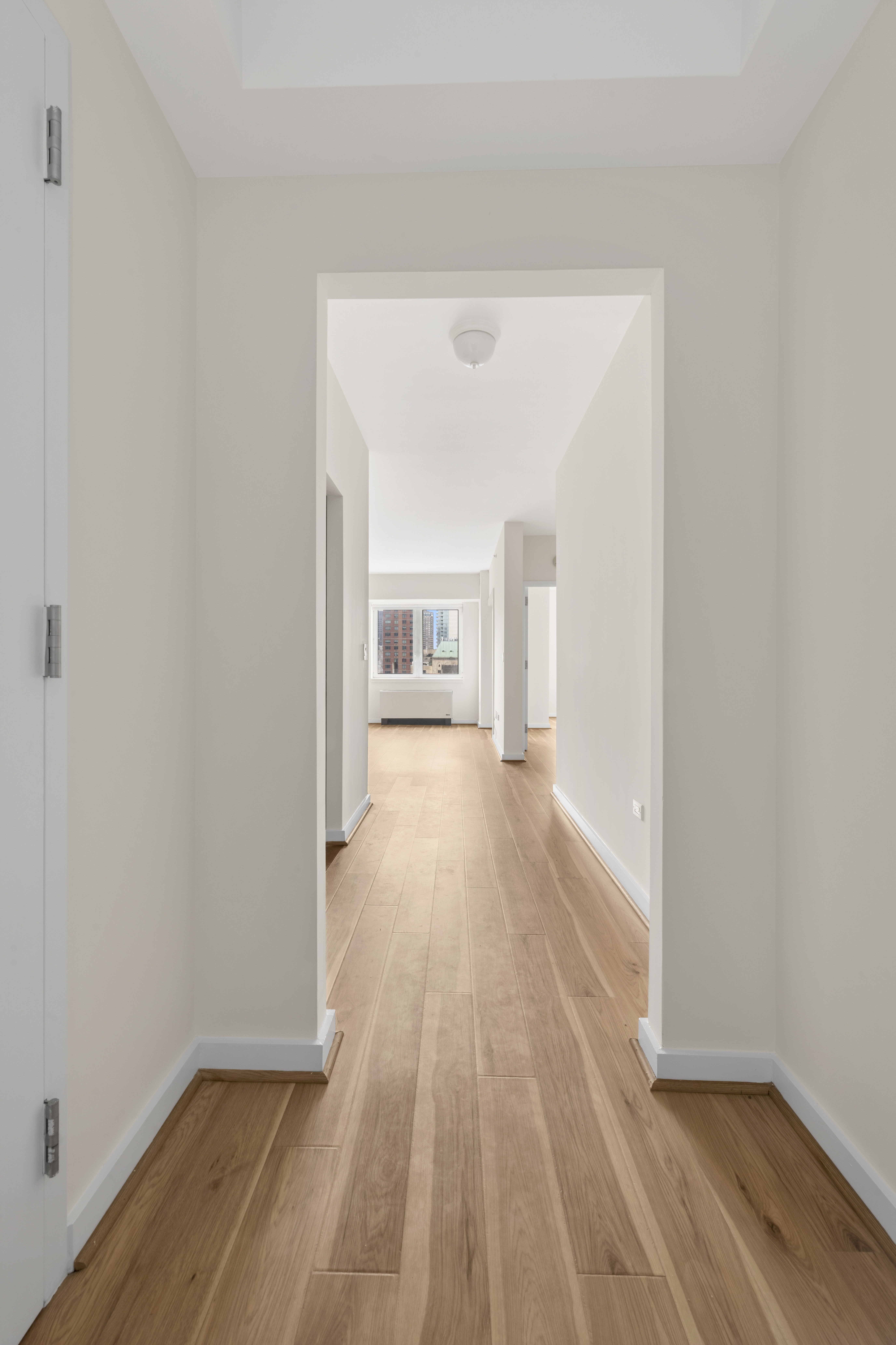 425 5th Avenue, Unit 23D Manhattan, NY 10016 - Photo 7 of 20 a view of a hallway with wooden floor and a living room