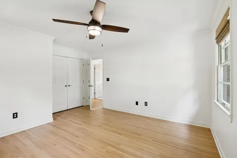 an empty room with wooden floor cabinet and windows