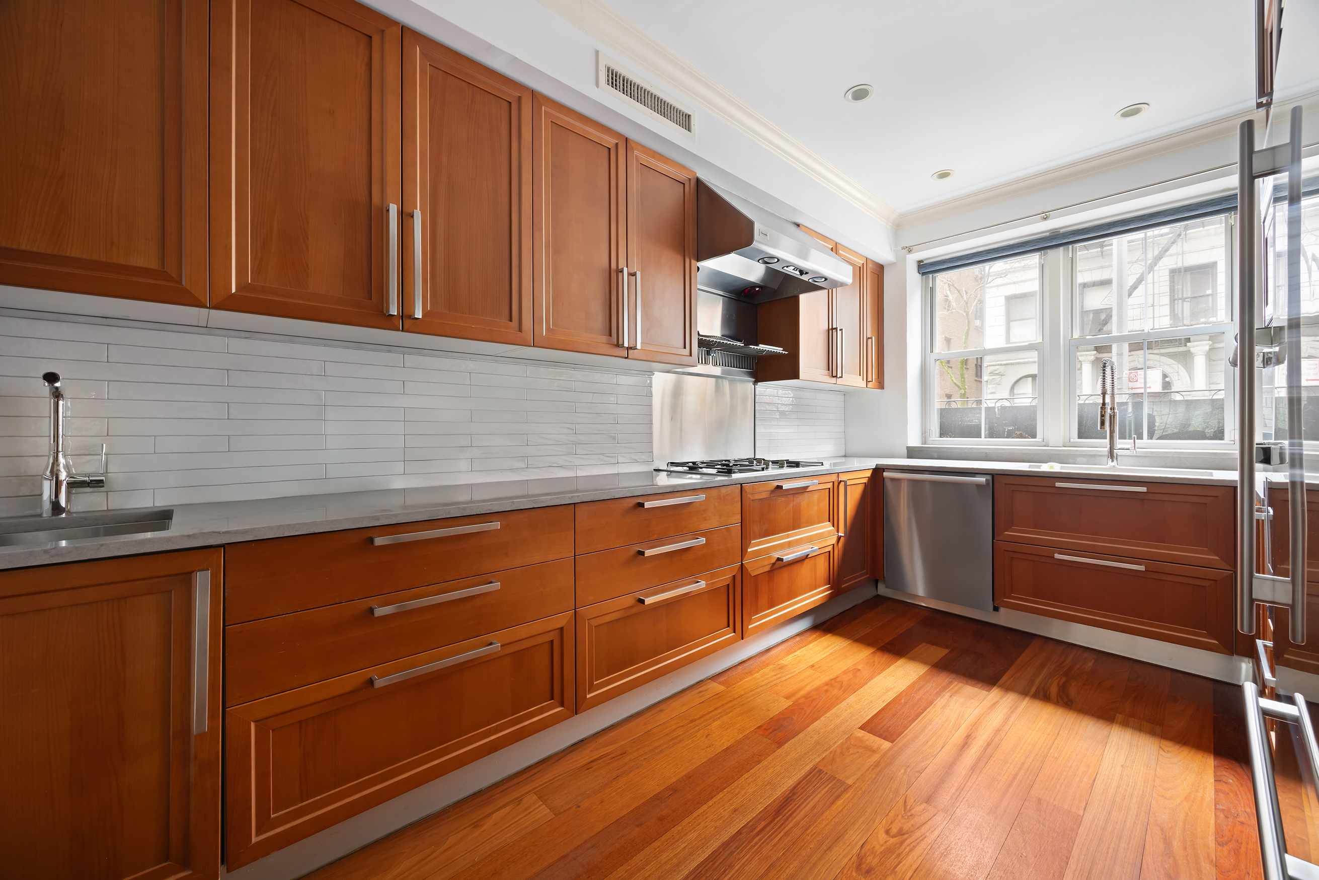 217 West 22nd Street Manhattan, NY 10011 - Photo 6 of 16 a kitchen with stainless steel appliances granite countertop a sink a stove cabinets and a wooden floor
