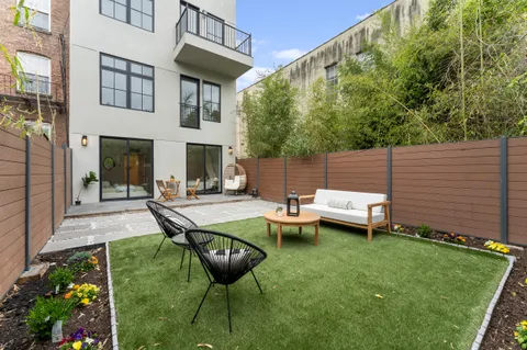 a view of a backyard with table and chairs potted plants and large tree