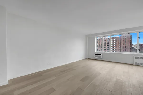 a view of an empty room with a window and wooden floor
