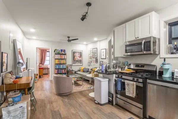 a kitchen with stainless steel appliances granite countertop a stove top oven a sink dishwasher and white cabinets with wooden floor