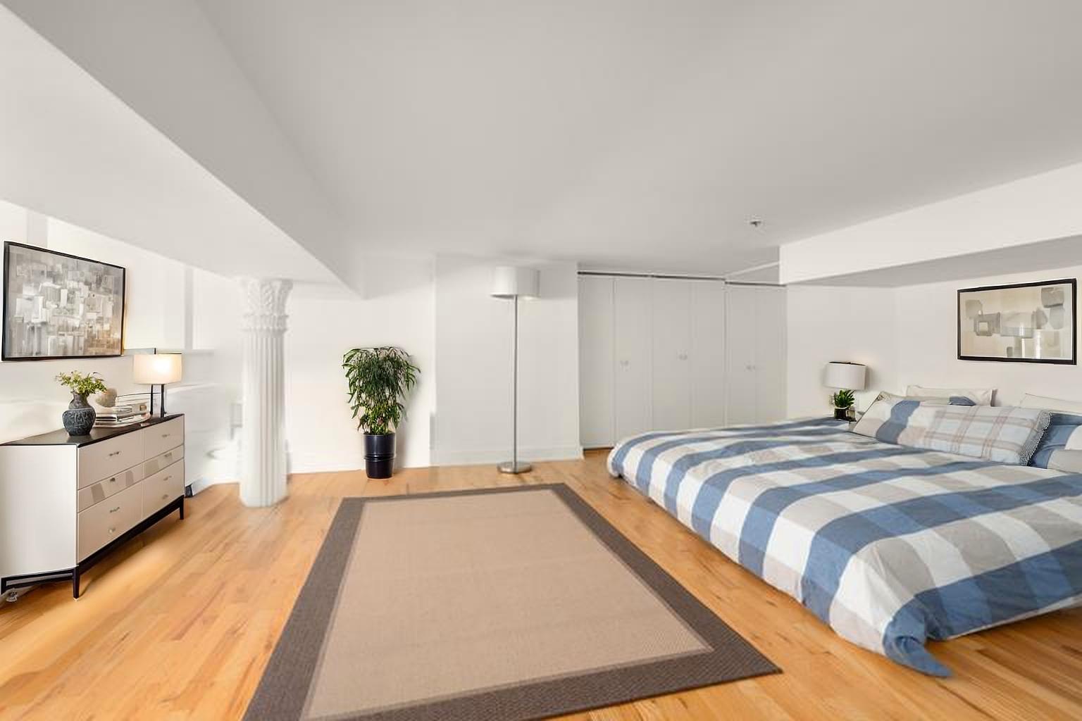 77 Bleecker Street, Unit 618 Manhattan, NY 10012 - Photo 3 of 6 a spacious bedroom with a bed and a large mirror