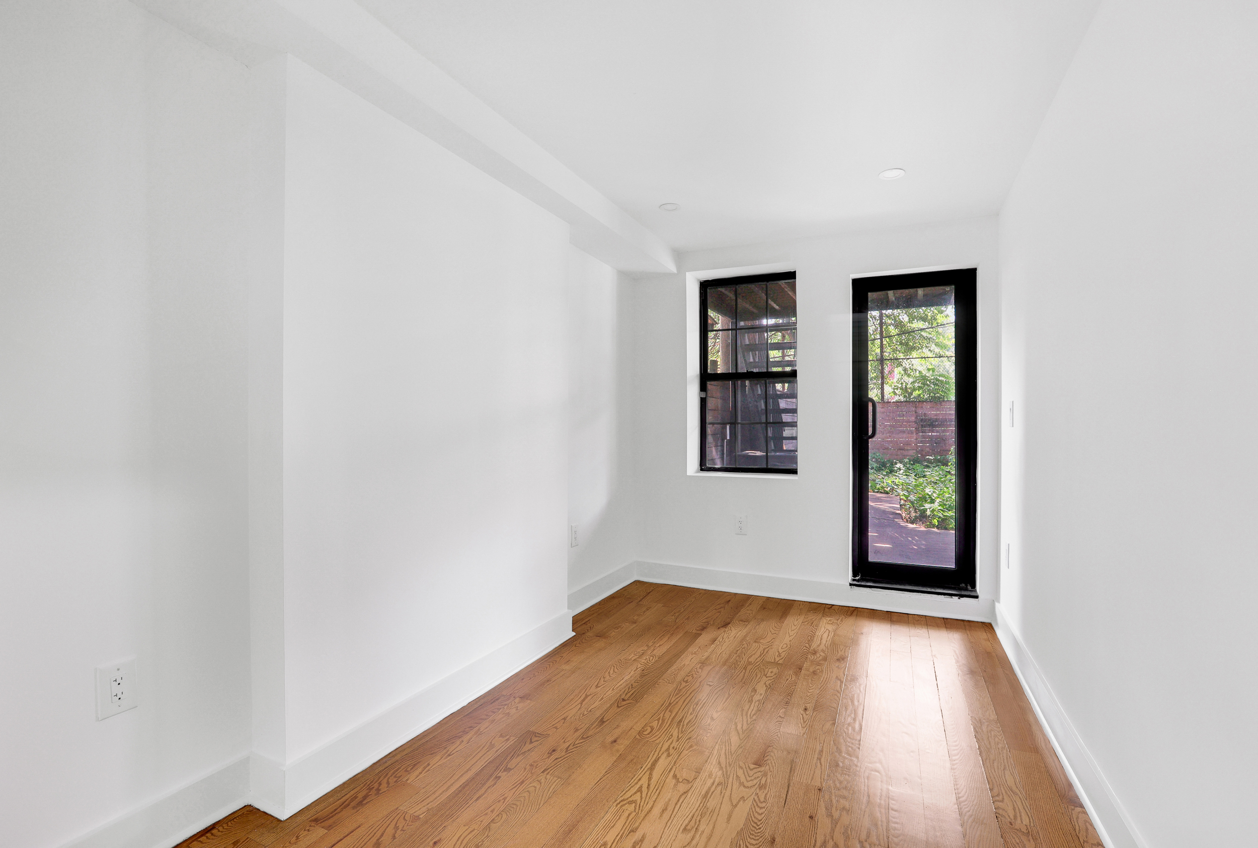 846 Hancock Street, Unit GARDEN Brooklyn, NY 11233 - Photo 6 of 17 an empty room with wooden floor and windows