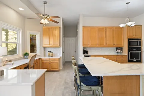 a kitchen with granite countertop a sink a stove a dining table and chairs
