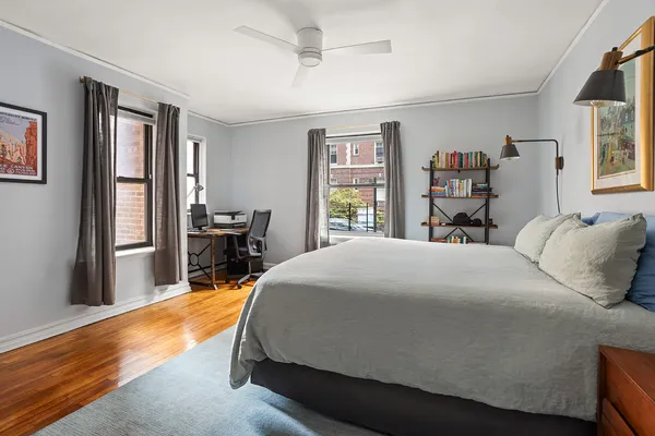 a bed sitting in a bedroom next to a window with a bookshelf