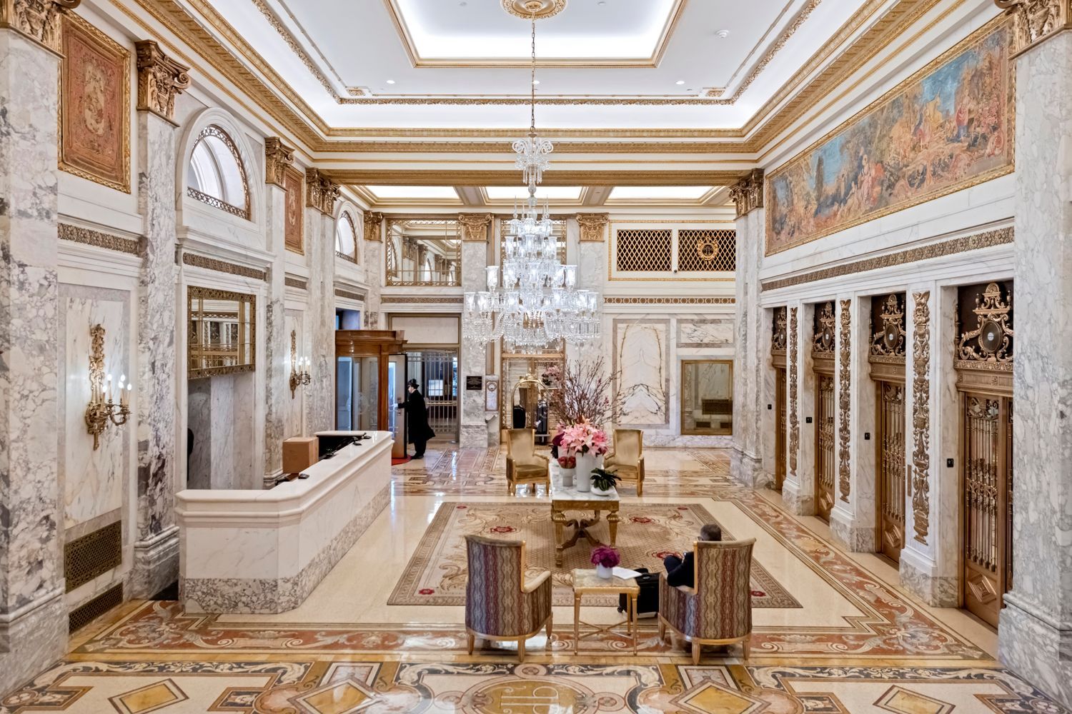a room with lots of white furniture and chandelier