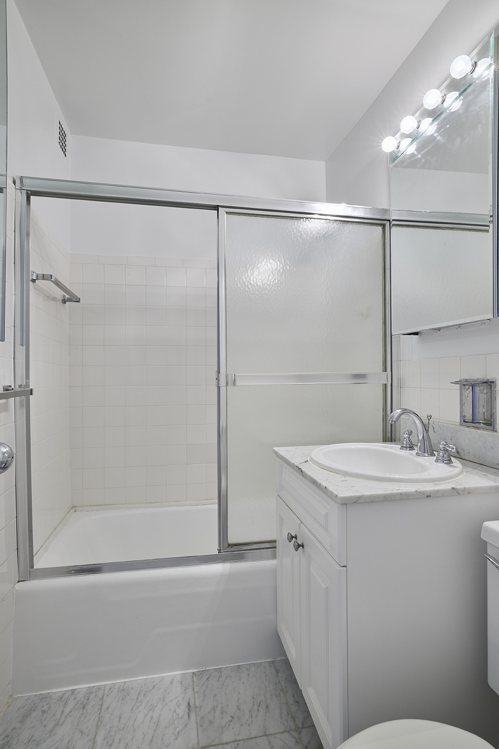 180 West End Avenue, Unit 27A Manhattan, NY 10023 - Photo 13 of 18 a bathroom with a shower sink vanity and mirror