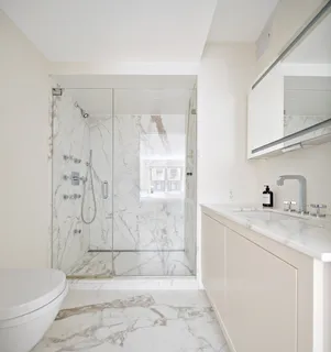 a bathroom with a granite countertop sink a toilet and shower