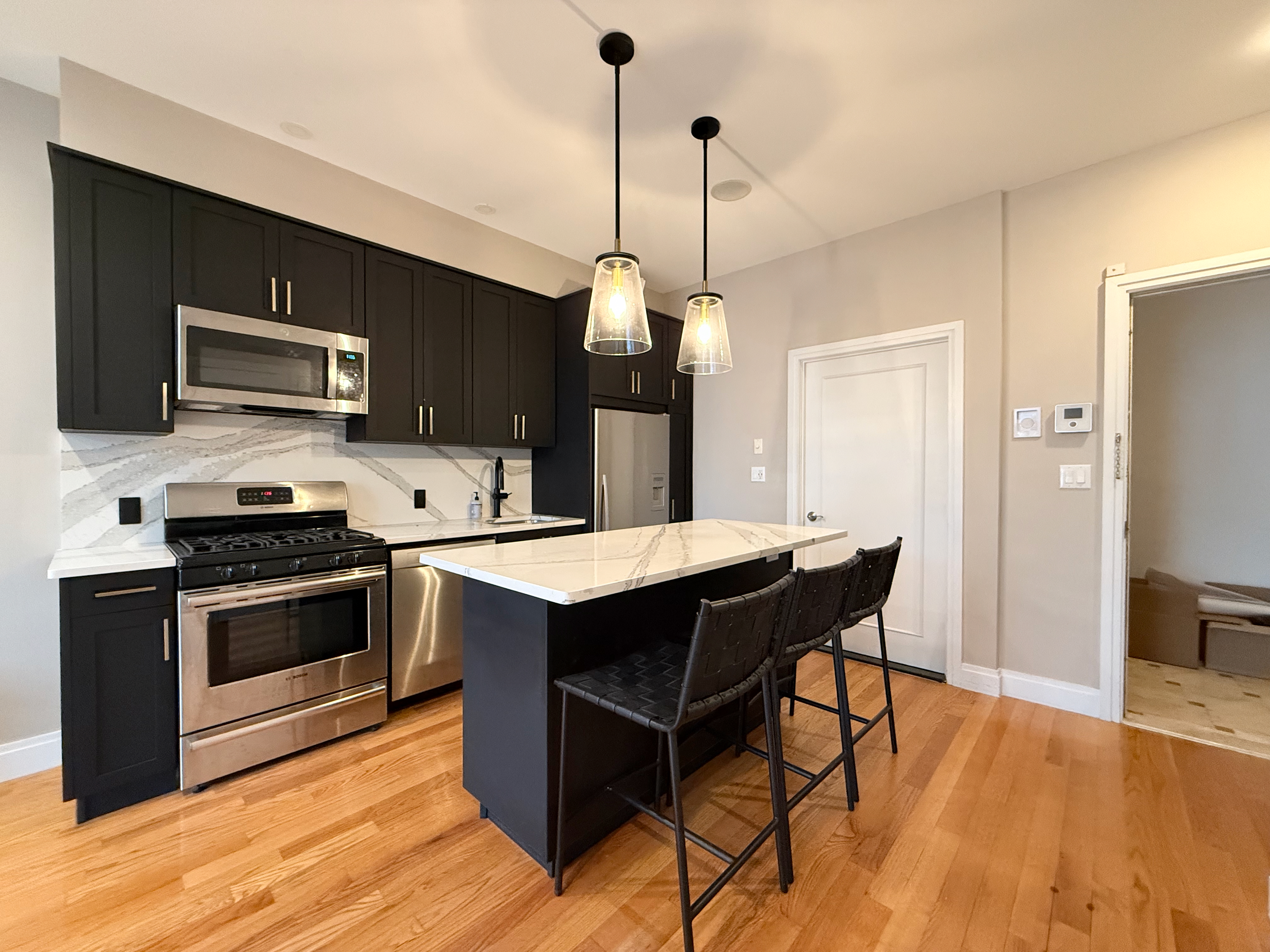 151 Green Street, Unit 2A Brooklyn, NY 11222 - Photo 2 of 6 a kitchen with stainless steel appliances kitchen island granite countertop a stove a sink dishwasher a refrigerator and a fireplace with wooden floor