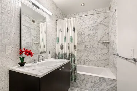 a bathroom with a granite countertop sink a bathtub and a shower