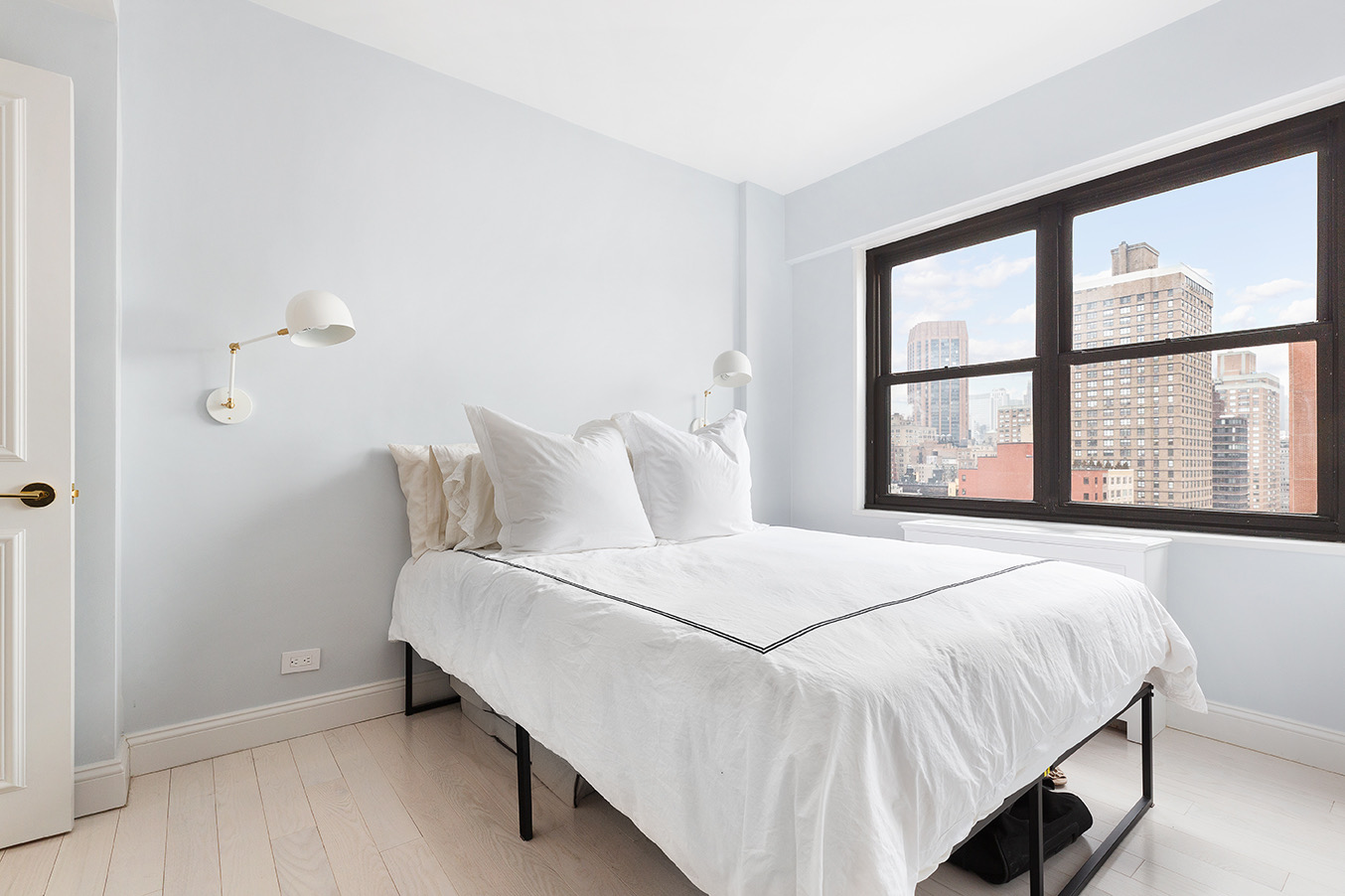 200 East 27th Street, Unit 19C Manhattan, NY 10016 - Photo 5 of 8 a large bed sitting in a bedroom next to a window