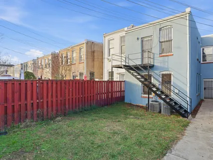 a view of a backyard with wooden fence and a large tree