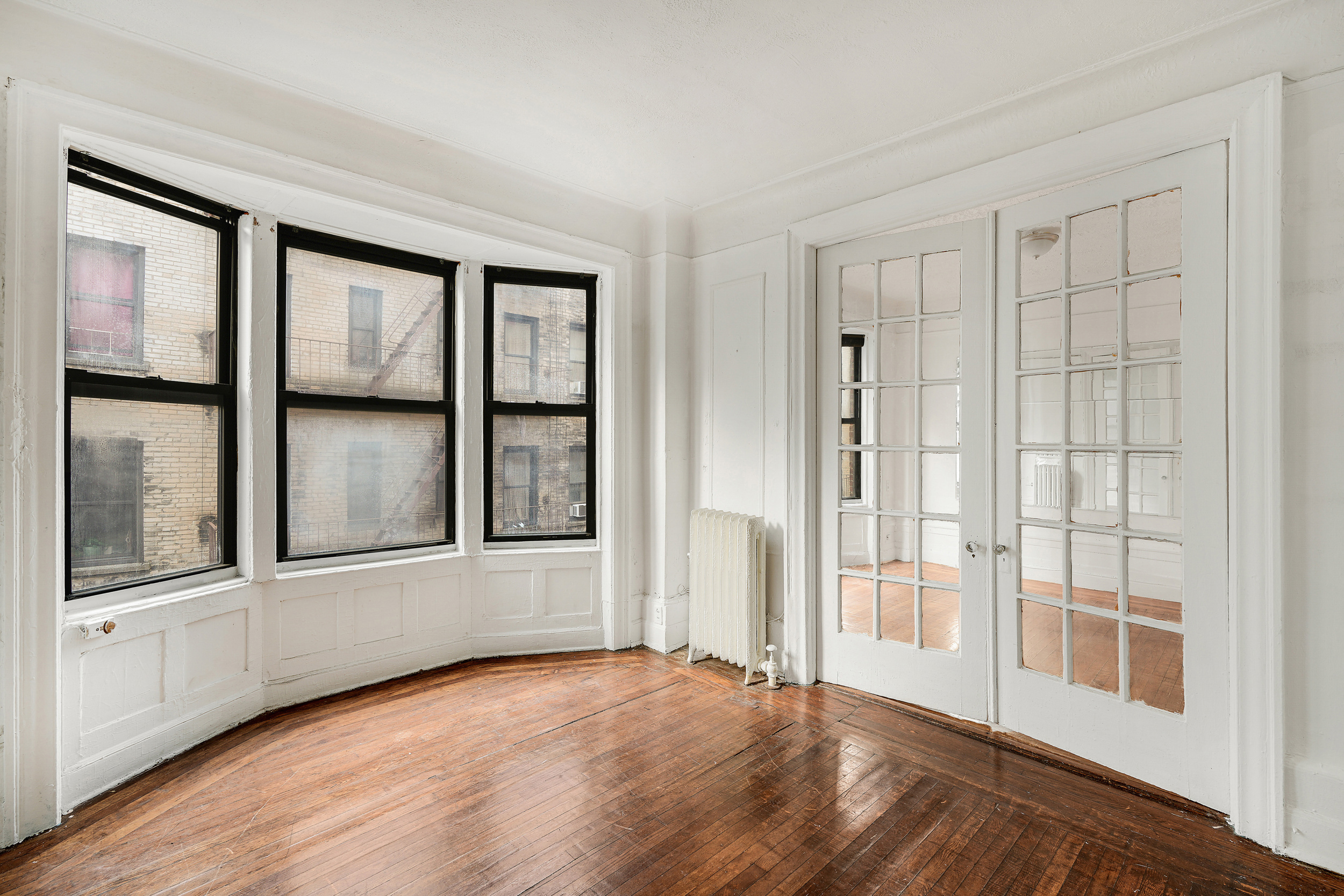 544 West 157th Street, Unit 44 Manhattan, NY 10032 - Photo 3 of 9 an empty room with wooden floor and windows