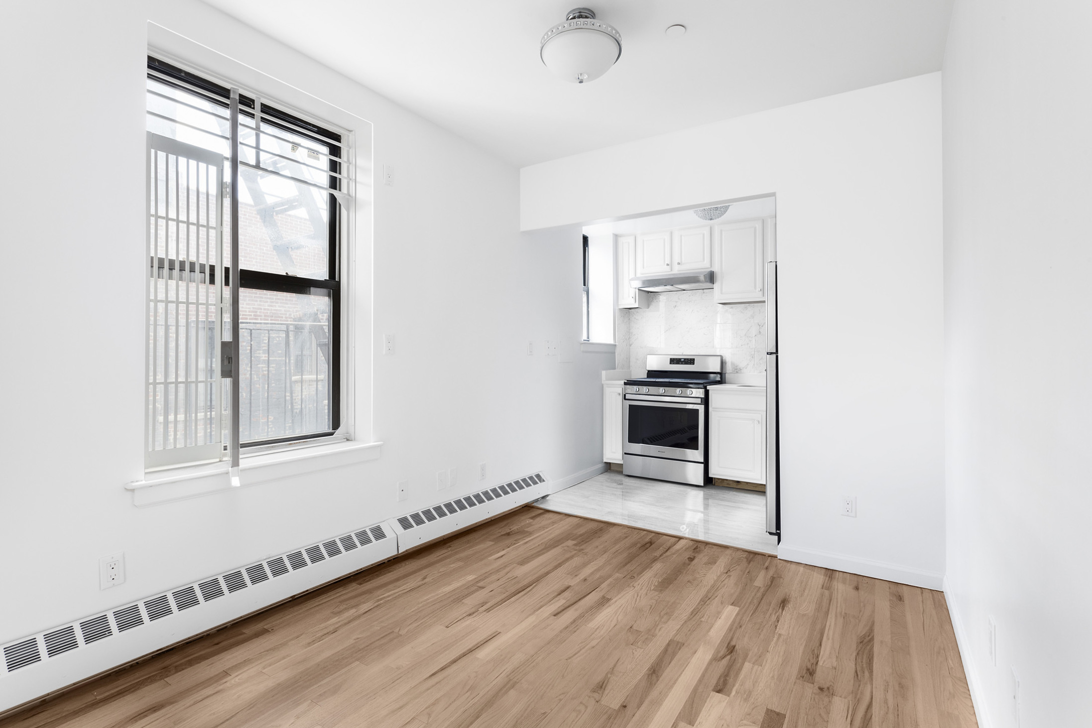 660 St Nicholas Avenue, Unit 63 Manhattan, NY 10030 - Photo 2 of 14 an empty room with wooden floor cabinet and windows
