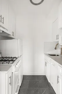 a kitchen with granite countertop a sink a stove and cabinets