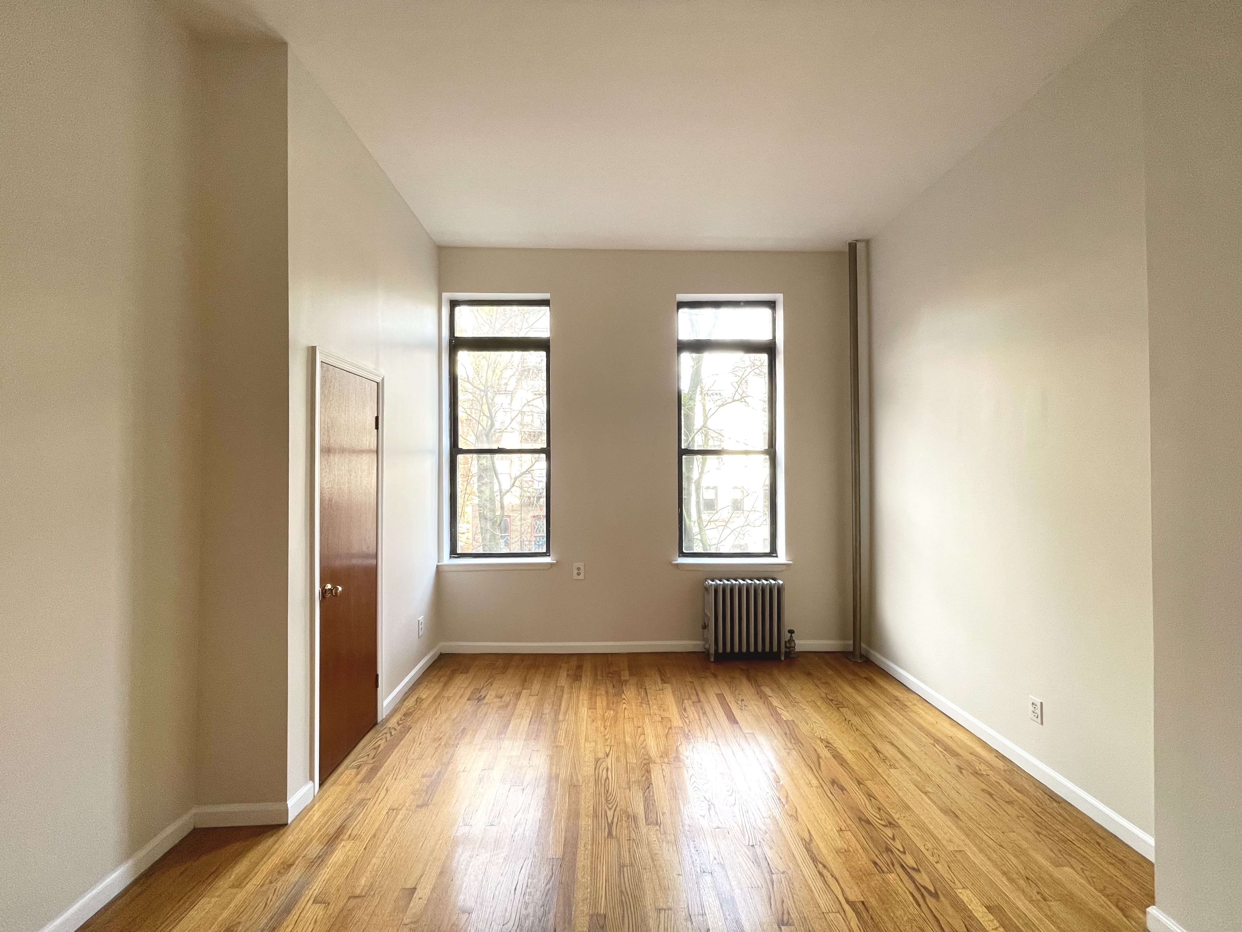 95 St Marks Place, Unit 6 Manhattan, NY 10009 - Photo 9 of 14 an empty room with wooden floor and windows