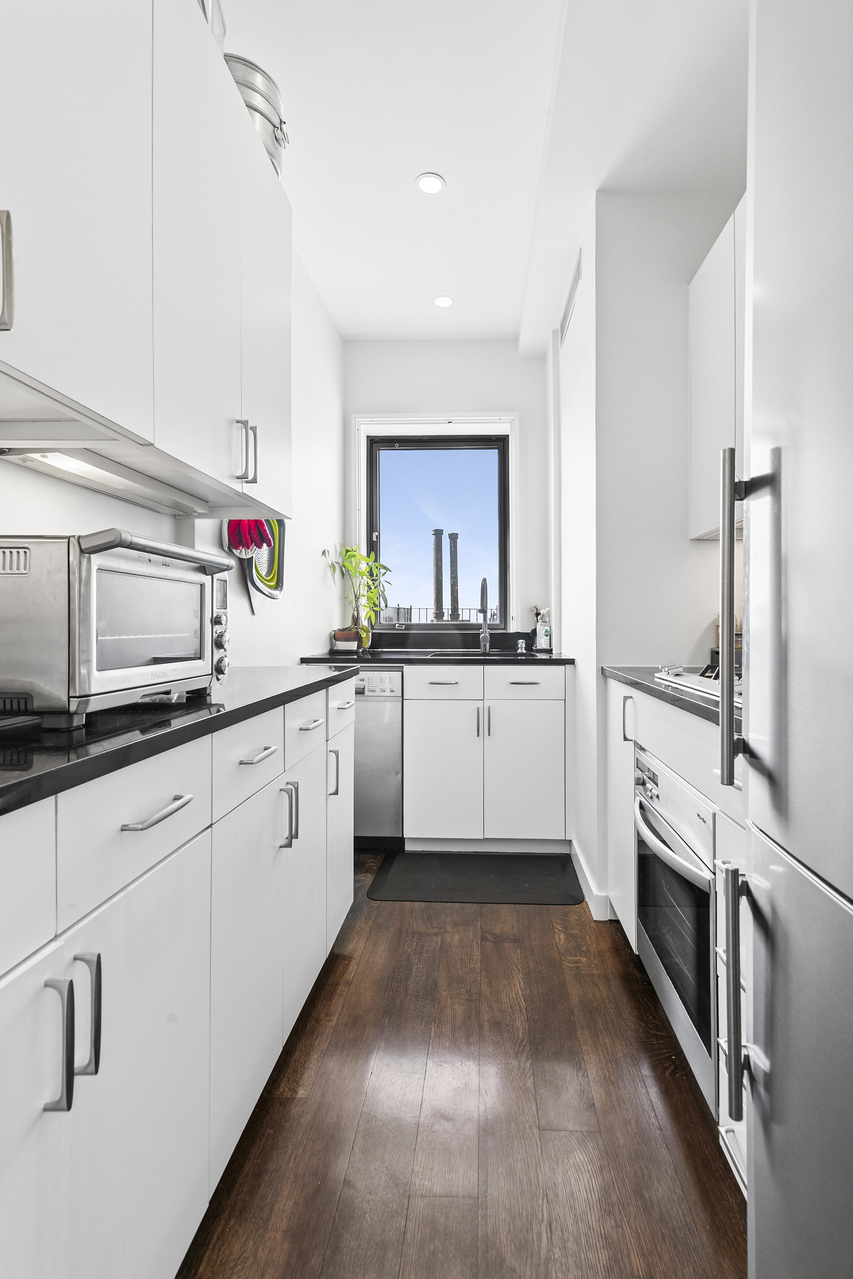 310 West 106th Street, Unit PH17B Manhattan, NY 10025 - Photo 4 of 9 a kitchen with granite countertop a sink stainless steel appliances and white cabinets