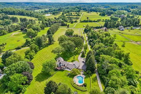 an aerial view of a house with swimming pool and green space