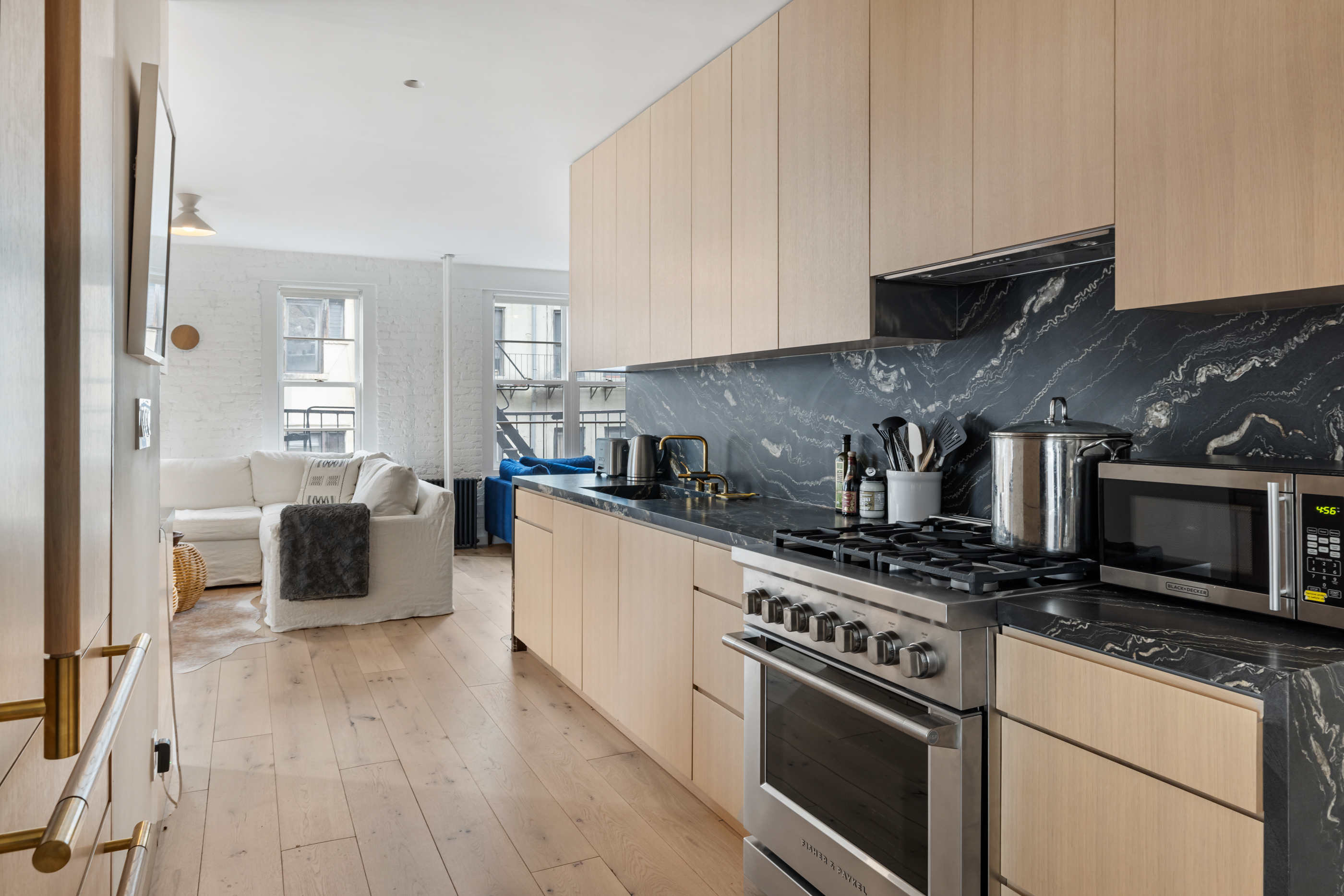 57 Thompson Street, Unit 4E Manhattan, NY 10012 - Photo 4 of 16 a kitchen with stainless steel appliances granite countertop a stove a sink and a microwave