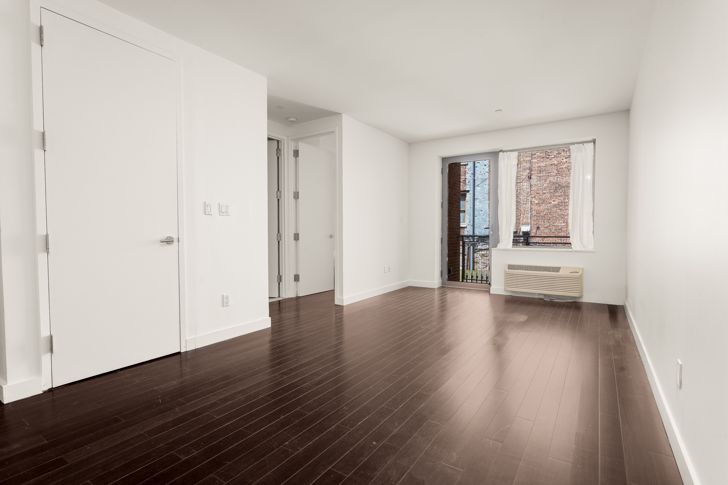 753 St Nicholas Avenue, Unit 2B Manhattan, NY 10031 - Photo 2 of 10 an empty room with wooden floor and windows