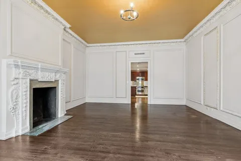 a view of an empty room with wooden floor and a fireplace