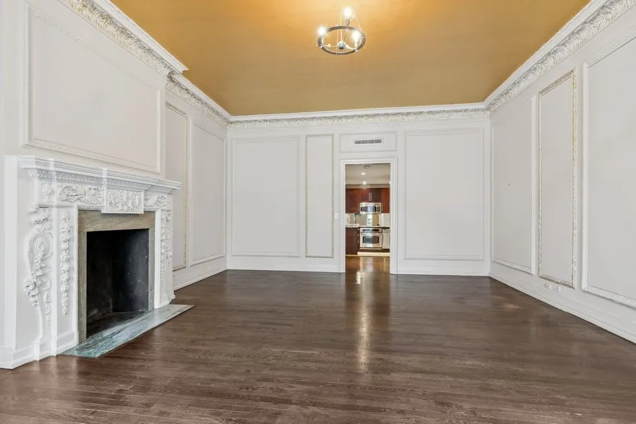 a view of an empty room with wooden floor and a fireplace